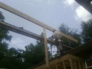 Carpenter setting a ridge beam over a new addition frame — Ice Dam Removal by Roofing Brothers in Pontiac
