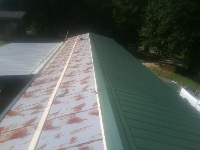 Old rusted panels beside newly installed green metal roofing — Wind Damage Roof Repair by Roofing Brothers in Pontiac