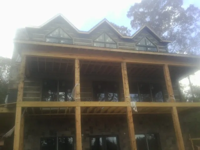 Dormers and porch framing on a large log home under construction — Roof Coating work by our crew in Pontiac