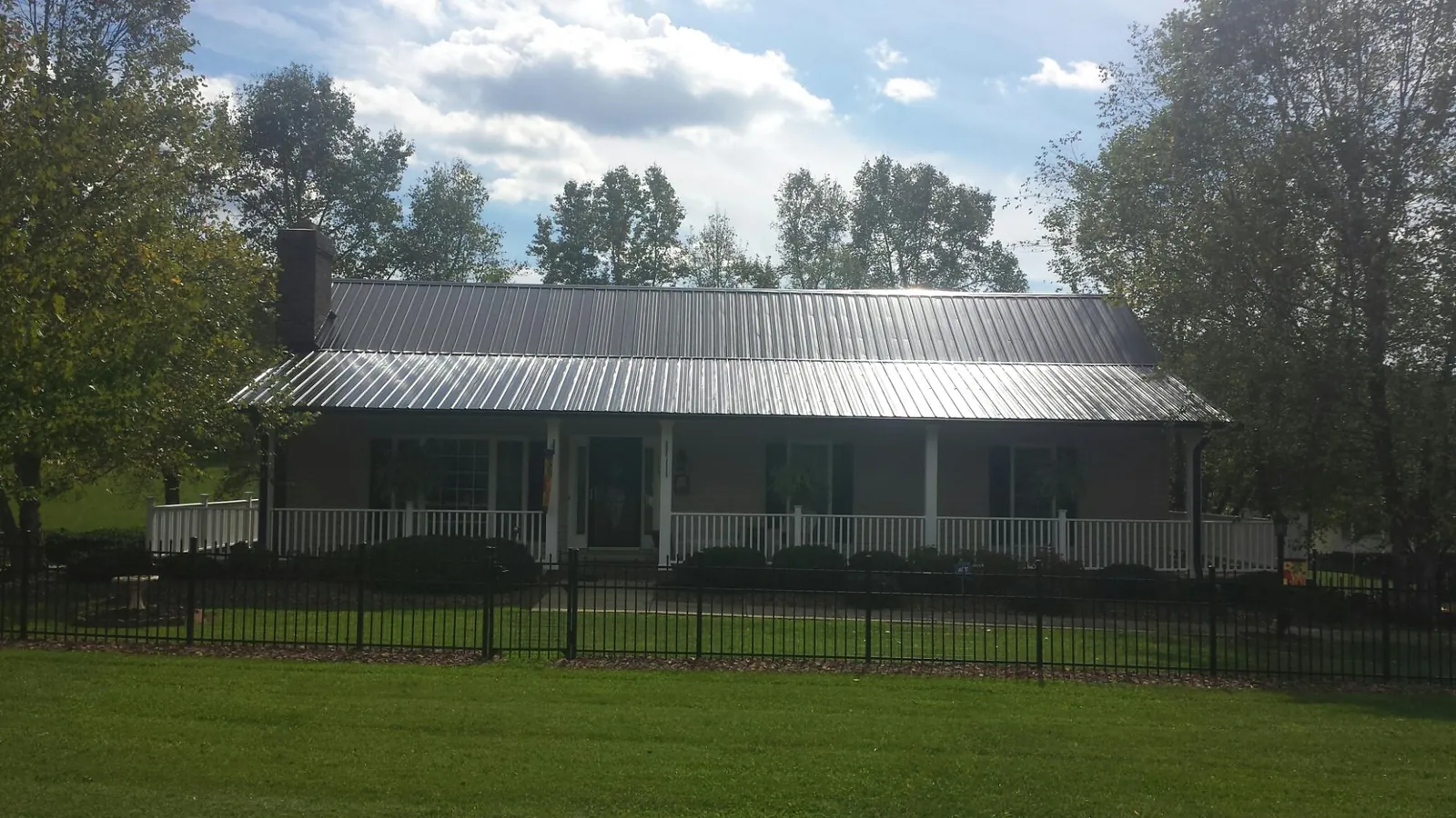 Gray metal roof on a brick ranch with a full width front porch — Gutter Guard Installation work by our crew in Pontiac